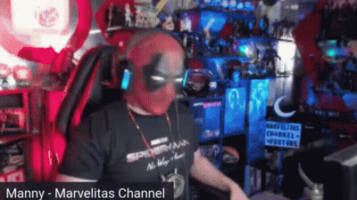 A Man Wearing A Deadpool Mask And Headphones Is Sitting In A Chair . GIF