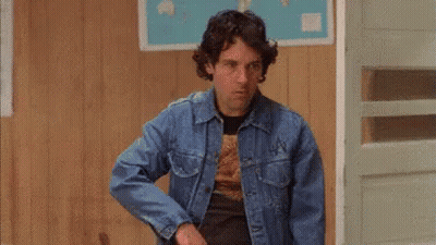 A Man Wearing A Denim Jacket And Sunglasses Is Standing In A Room . GIF
