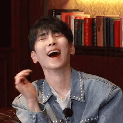 A Man Wearing A Denim Jacket With Pearls On The Collar Is Laughing GIF
