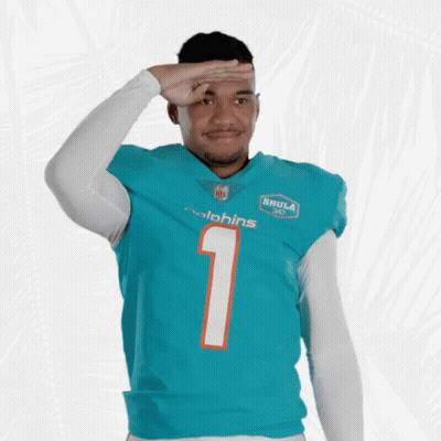 A Man Wearing A Dolphins Jersey Salutes In Front Of A White Background GIF