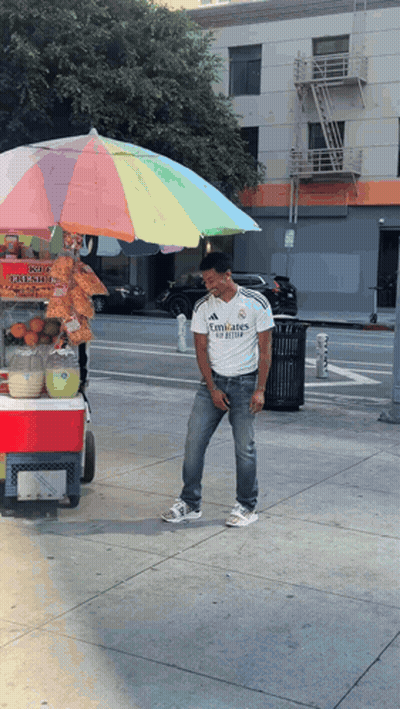 A Man Wearing A Emirates Shirt Stands In Front Of A Cart GIF