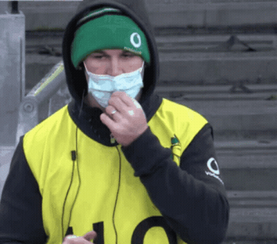 A Man Wearing A Face Mask And A Green Hat With The Number 0 On It GIF