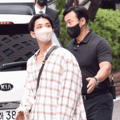 A Man Wearing A Face Mask Is Walking By A Kia Car GIF