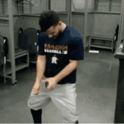 A Man Wearing A Famous Baseball Shirt Is Dancing In A Locker Room . GIF
