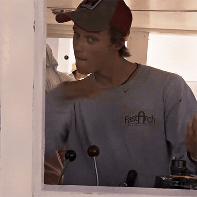 A Man Wearing A Fast Arch T-Shirt Looks Out Of A Window GIF
