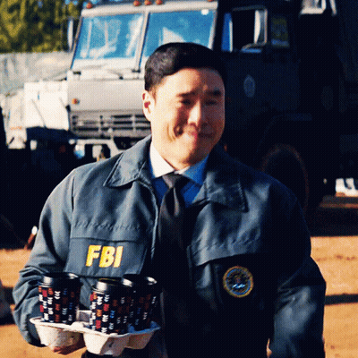 A Man Wearing A Fbi Jacket Carrying A Tray Of Coffee Cups GIF