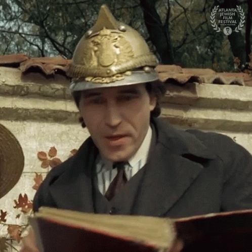 A Man Wearing A Fire Helmet Is Reading A Book GIF