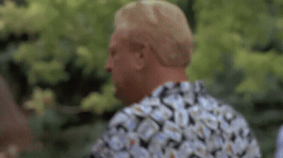 A Man Wearing A Floral Shirt Is Standing In Front Of A Tree . GIF