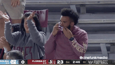 A Man Wearing A Florida Sweatshirt Wipes His Nose During A Football Game GIF