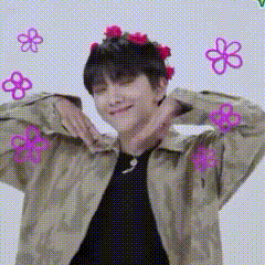 A Man Wearing A Flower Crown Is Making A Heart With His Hands . GIF
