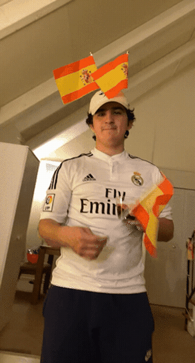 A Man Wearing A Fly Emirates Shirt Is Holding A Small Spanish Flag GIF