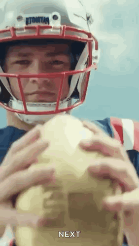A Man Wearing A Football Helmet Is Holding A Football In His Hands And Says Next . GIF