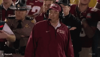 A Man Wearing A Fsu Jacket Is Standing In Front Of A Crowd . GIF