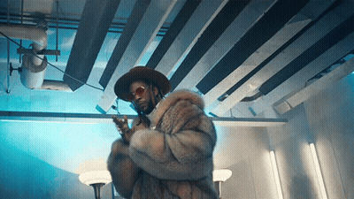 A Man Wearing A Fur Coat And A Hat Holds A Gun GIF