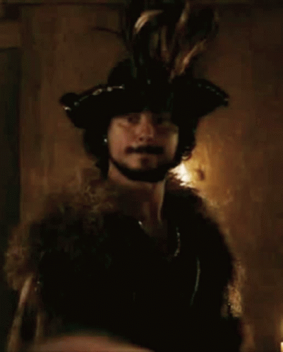 A Man Wearing A Fur Coat And A Hat With Feathers On It GIF