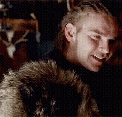 A Man Wearing A Fur Coat Is Smiling In Front Of A Deer Skull GIF