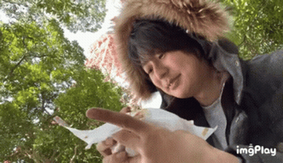 A Man Wearing A Fur Hood Is Holding A Piece Of Paper In His Hand . GIF