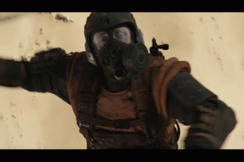 A Man Wearing A Gas Mask And A Helmet With A Gun GIF