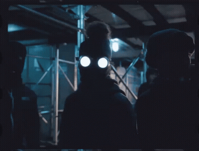 A Man Wearing A Gas Mask And Glasses Stands In The Dark GIF