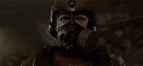 A Man Wearing A Gas Mask And Helmet Looks At The Camera GIF