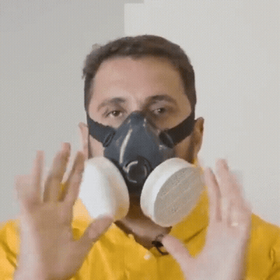 A Man Wearing A Gas Mask Holds His Hands Up GIF
