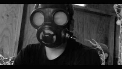 A Man Wearing A Gas Mask Is Looking At The Camera GIF