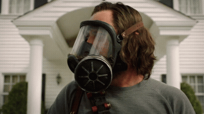 A Man Wearing A Gas Mask Is Standing In Front Of A House GIF