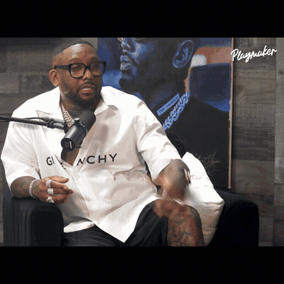 A Man Wearing A Givenchy Shirt Sits In Front Of A Playmaker Poster GIF