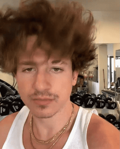 A Man Wearing A Gold Chain And A White Tank Top Stands In Front Of A Row Of Dumbbells That Say 30 Pounds GIF
