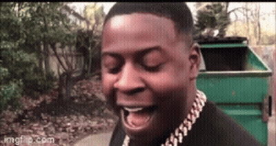 A Man Wearing A Gold Chain Around His Neck Is Laughing With His Mouth Open . GIF