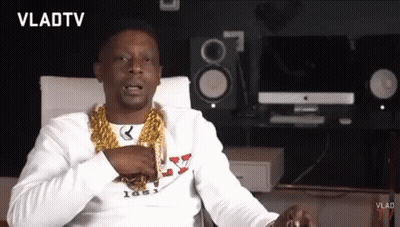A Man Wearing A Gold Chain Around His Neck Is Sitting In Front Of A Vlad Tv Logo GIF