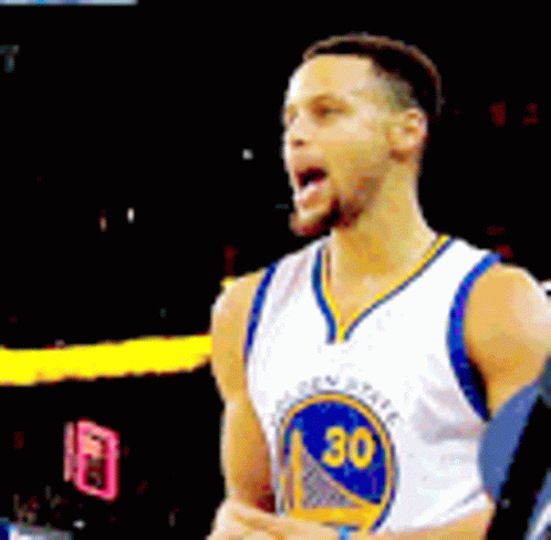 A Man Wearing A Golden State Warriors Jersey Is Standing On A Basketball Court . GIF