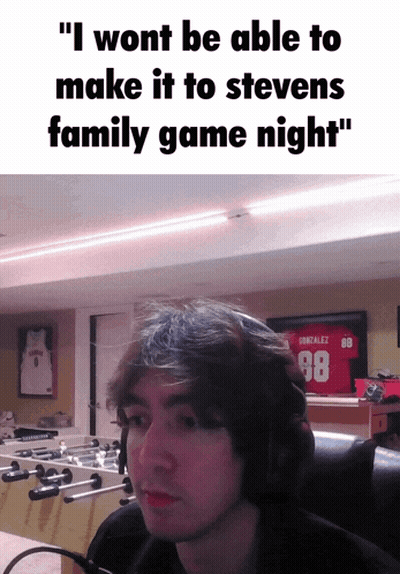 A Man Wearing A Gonzalez 98 Jersey Sits In Front Of A Foosball Table In A Room GIF