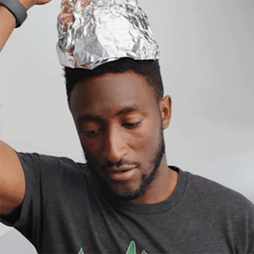 A Man Wearing A Gray Shirt Has A Piece Of Aluminum Foil On Top Of His Head GIF