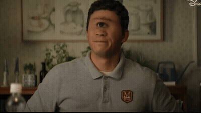A Man Wearing A Gray Shirt With The Letter M On The Front GIF