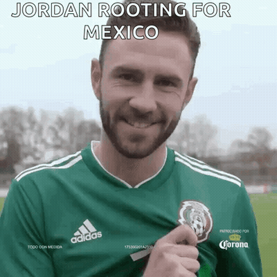 A Man Wearing A Green Adidas Jersey Is Holding A Trophy . GIF