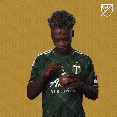 A Man Wearing A Green Airlines Shirt Holds A Cup GIF