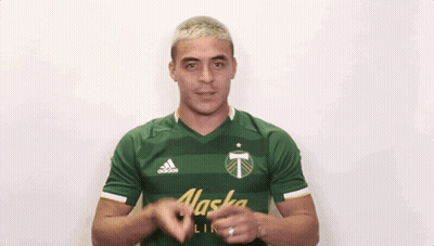 A Man Wearing A Green Alaska Shirt Is Clapping His Hands GIF