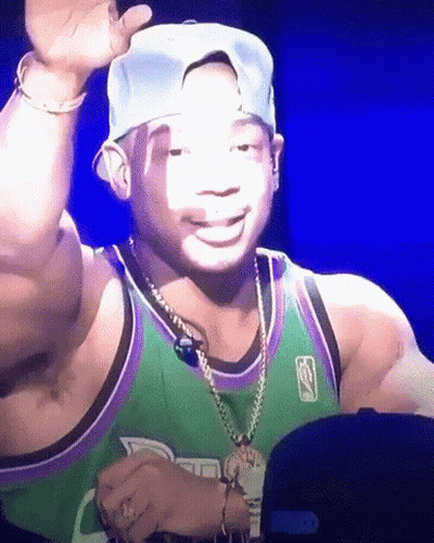 A Man Wearing A Green And Purple Jersey And A Hat Is Smiling GIF
