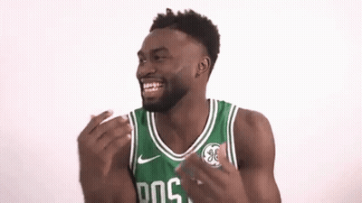 A Man Wearing A Green And White Boston Celtics Jersey Is Laughing With His Hands In The Air . GIF