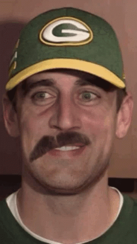 A Man Wearing A Green Bay Packers Hat With A Mustache . GIF