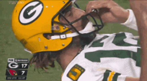 A Man Wearing A Green Bay Packers Helmet Is Laying On The Field GIF