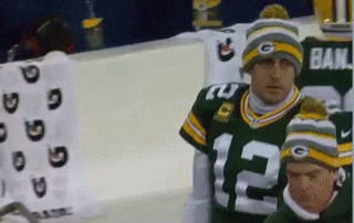 A Man Wearing A Green Bay Packers Jersey And A Beanie With The Number 12 On It GIF