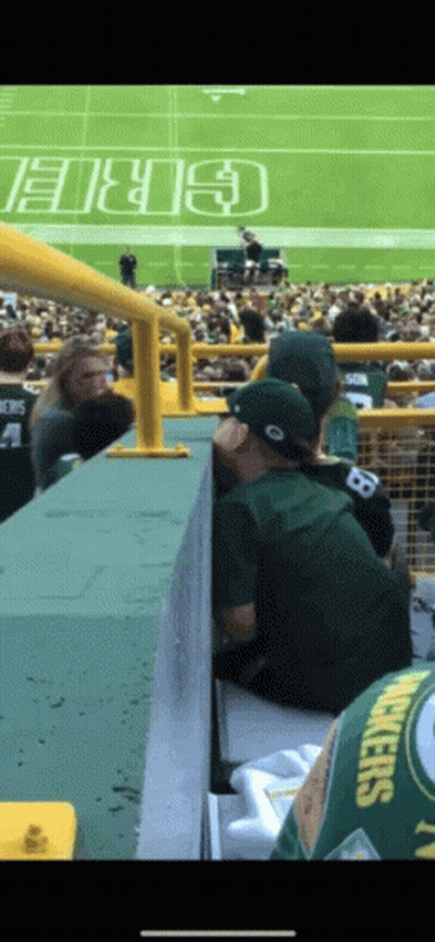 A Man Wearing A Green Bay Packers Jersey Sits On A Bleacher GIF