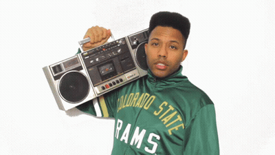 A Man Wearing A Green Colorado State Rams Jacket Is Holding A Boombox Over His Shoulder GIF