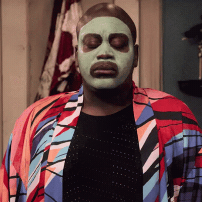 A Man Wearing A Green Face Mask And A Colorful Robe GIF