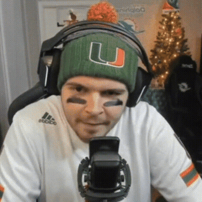 A Man Wearing A Green Hat With The Letter U On It Is Looking At His Phone GIF