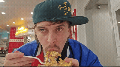 A Man Wearing A Green Hat With The Number 6 On It Is Eating French Fries GIF