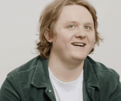 A Man Wearing A Green Jacket And A White Shirt Smiles For The Camera GIF
