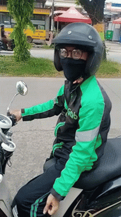 A Man Wearing A Green Jacket That Says Grab Is Sitting On A Motorcycle GIF